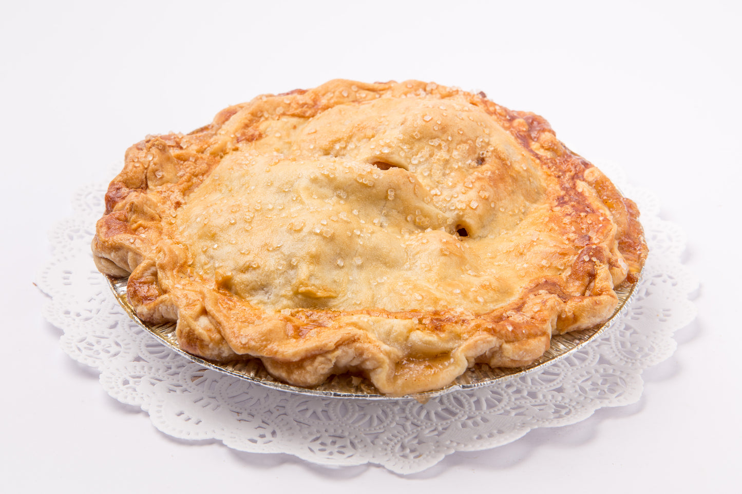 Pastry-topped pies on a white lace doily with a white background