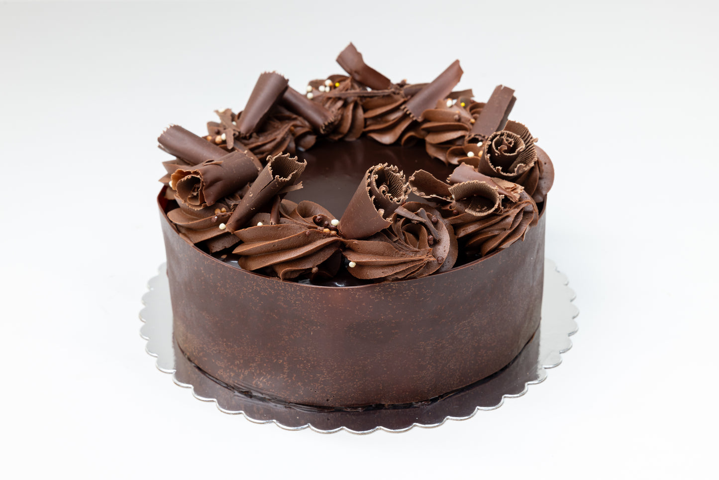 Chocolate cake with rosettes and chocolate curls on a white background