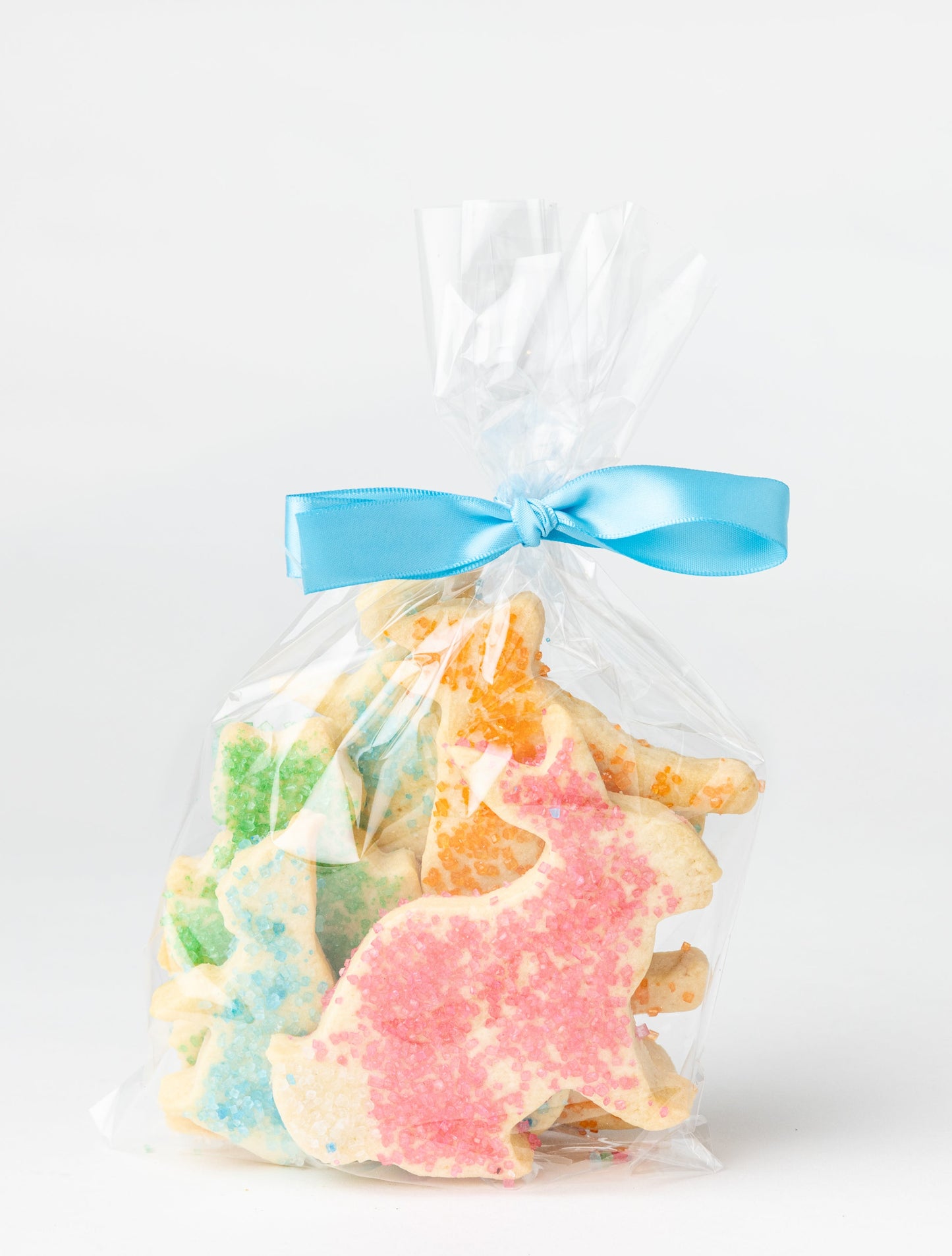 Bag of colorful animal-shaped cookies with a blue ribbon on a white background