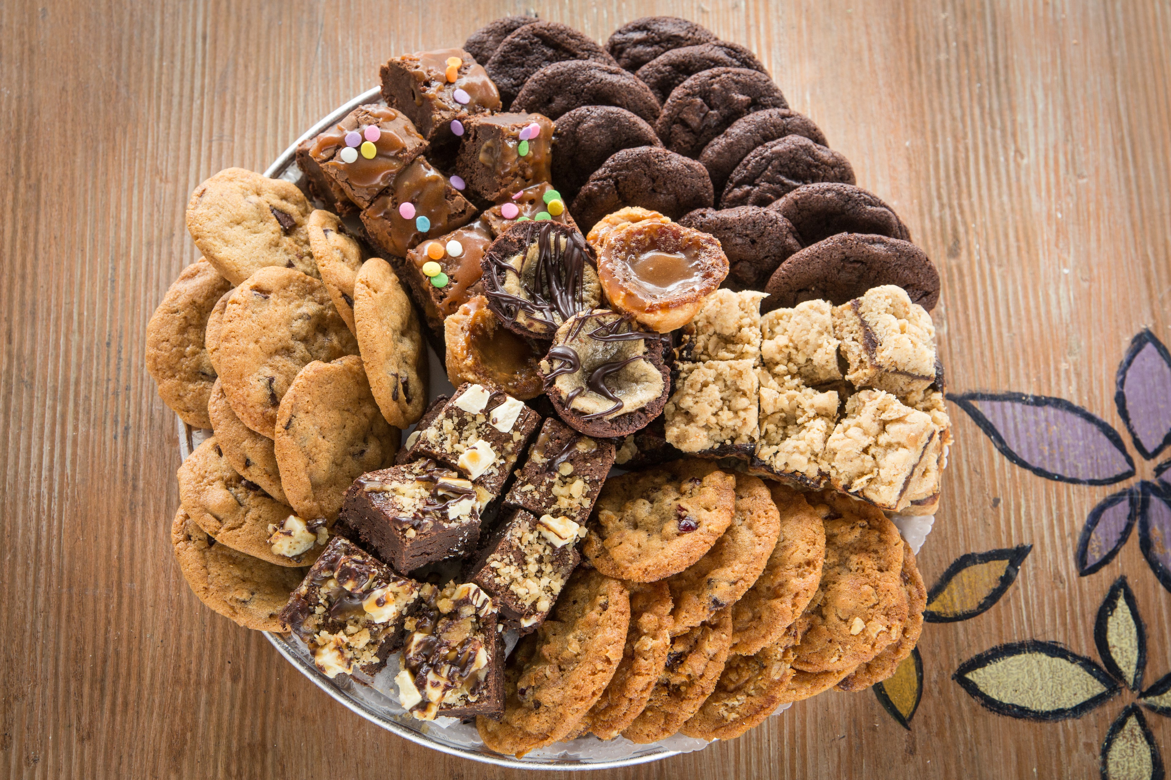 Assorted cookies and brownies on a platter on a wooden background