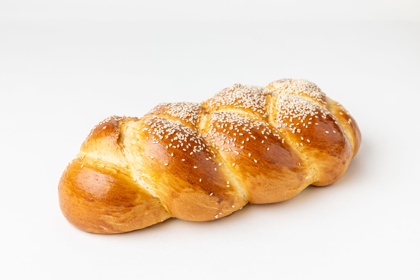 braided loaf with sesame seeds on a white background