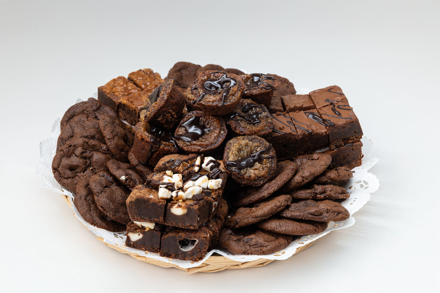 Assorted chocolate cookies and brownies on a white plate with a white background