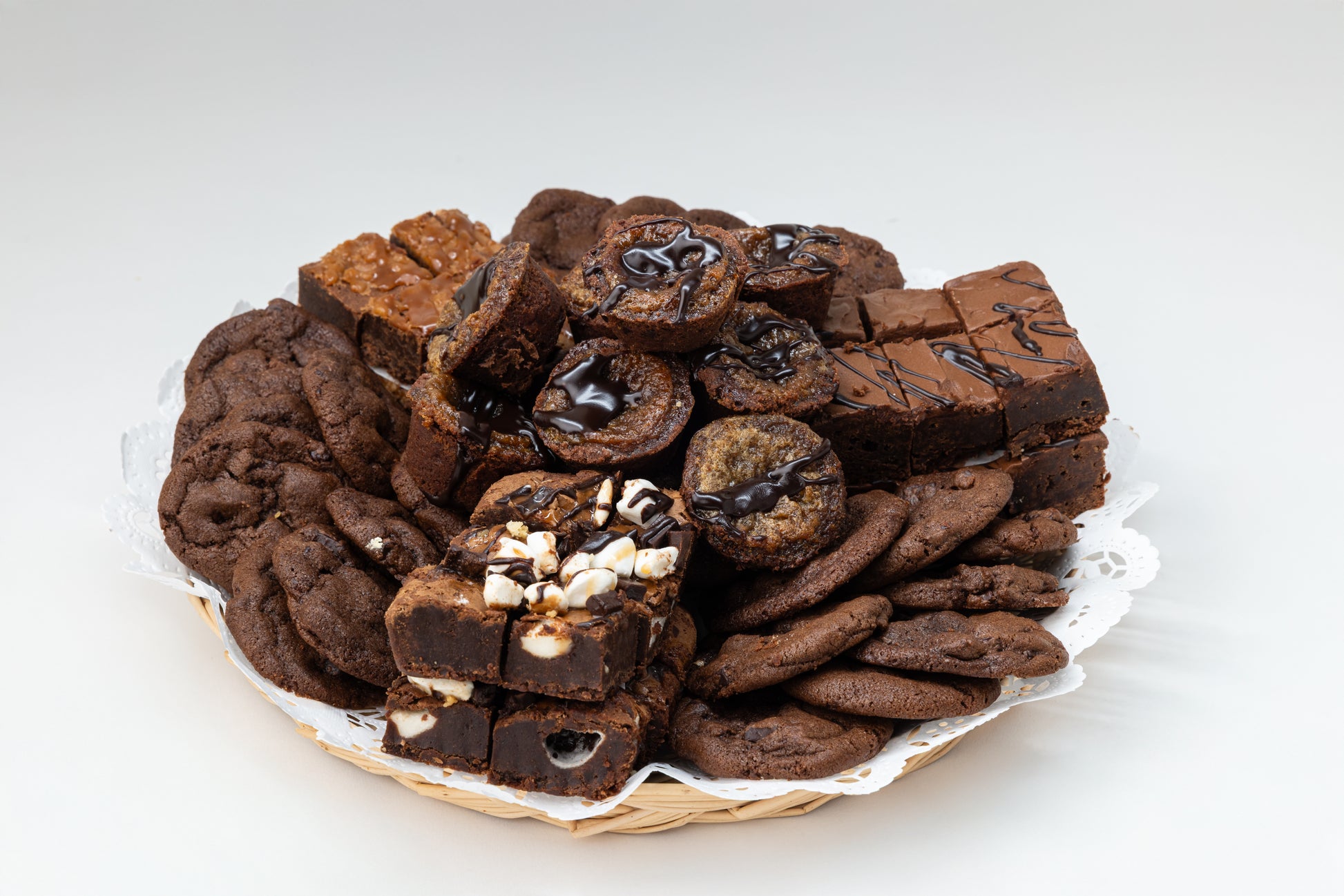 Assorted chocolate cookies and brownies on a white plate with a white background