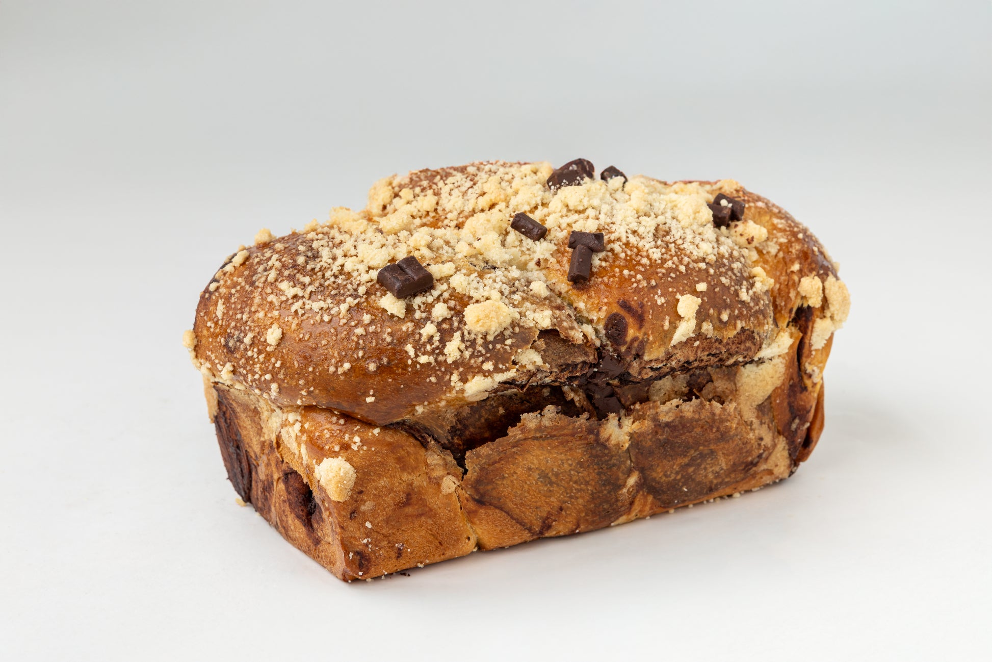 Babka in a loaf shape with chocolate chips and a crumbly topping on a white background
