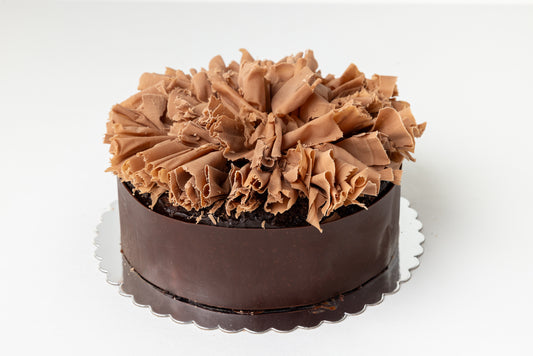 rolled chocolate wrapped around outside of cake and topped with milk chocolate curls