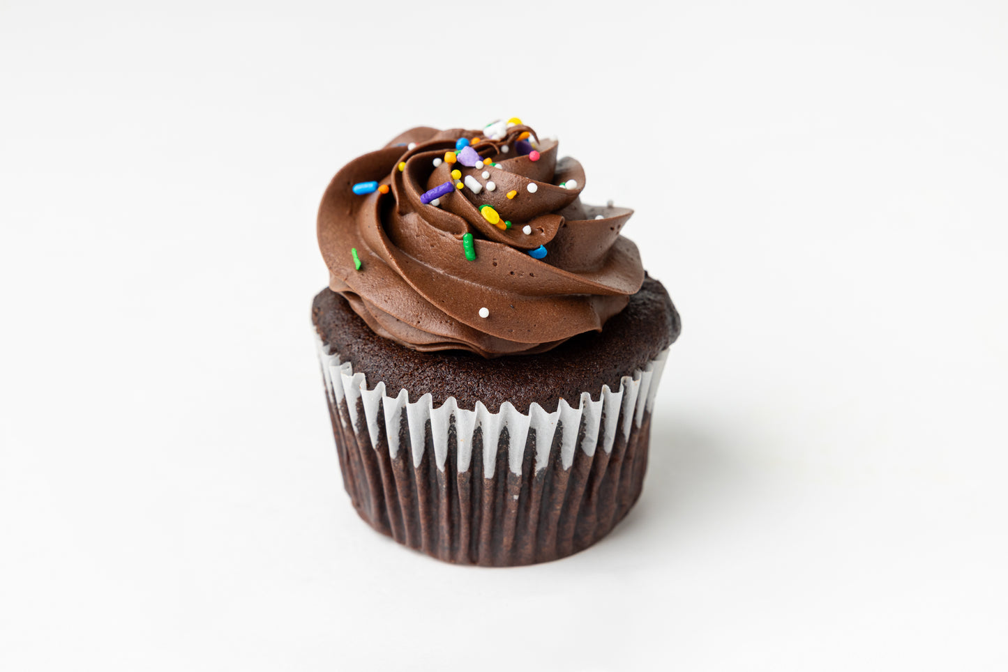 Chocolate cupcake with chocolate frosting and sprinkles on a white background