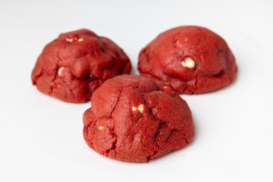 Three red cookies with white chocolate chips on a white background