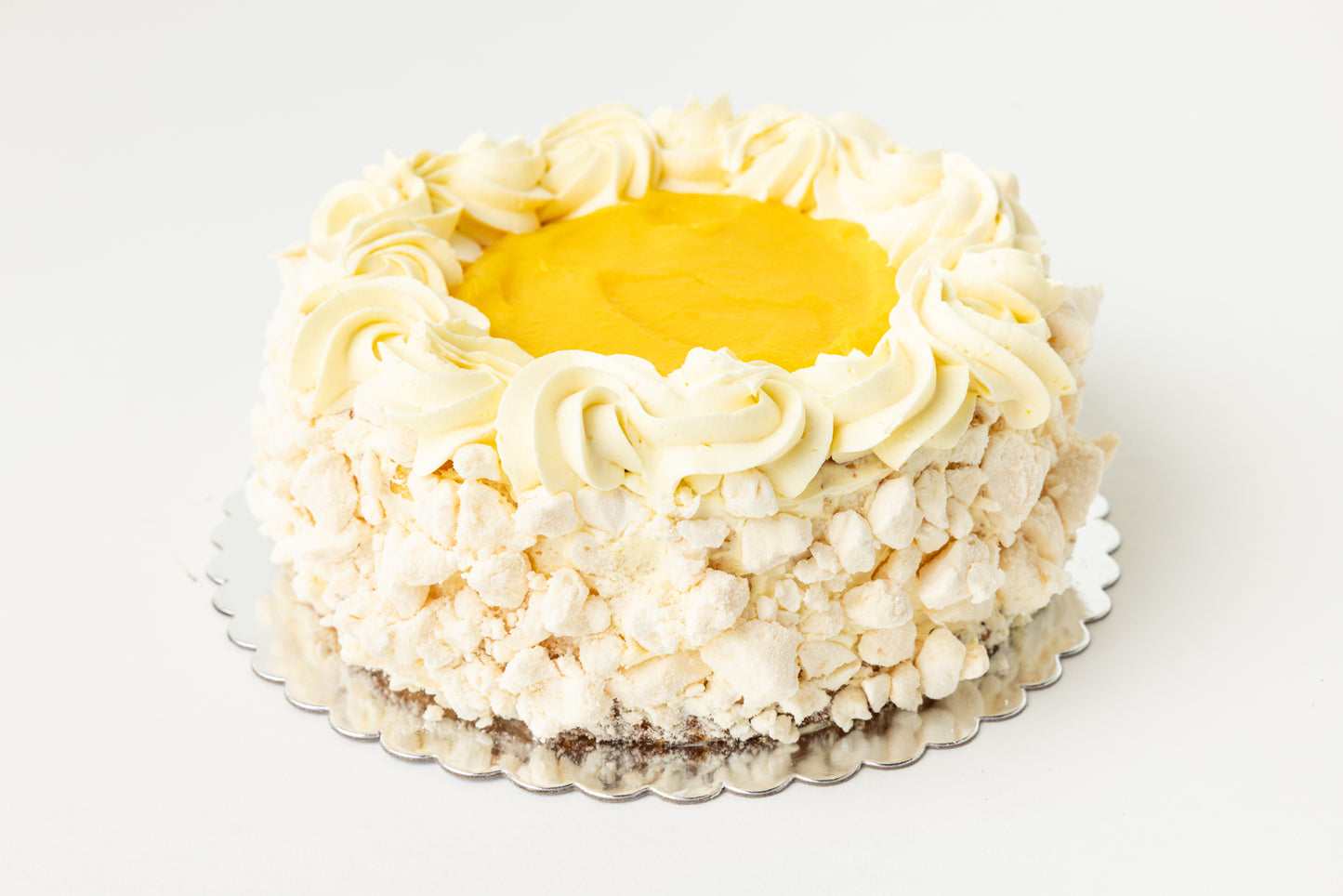 Lemon cheesecake with meringue, buttercream frosting and yellow lemon curd in the center all on a white background