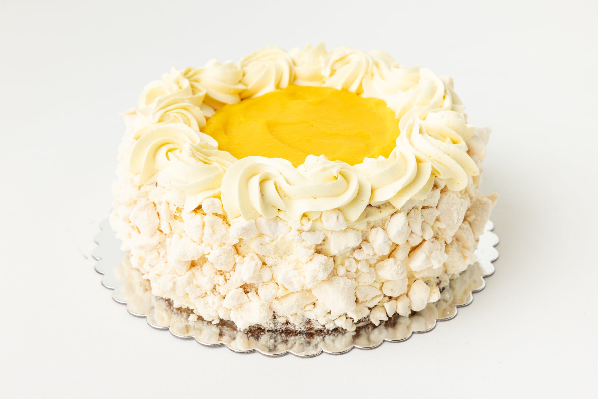 Lemon cheesecake with meringue, buttercream frosting and yellow lemon curd in the center all on a white background