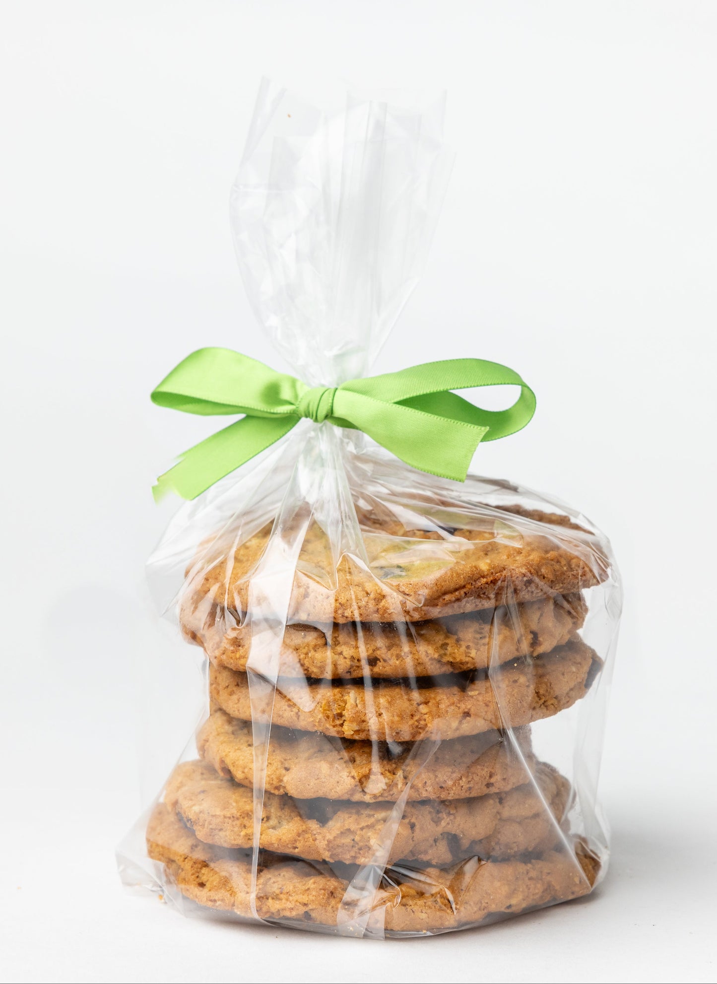 Stack of cookies in clear cellophane bag with green ribbon on white background