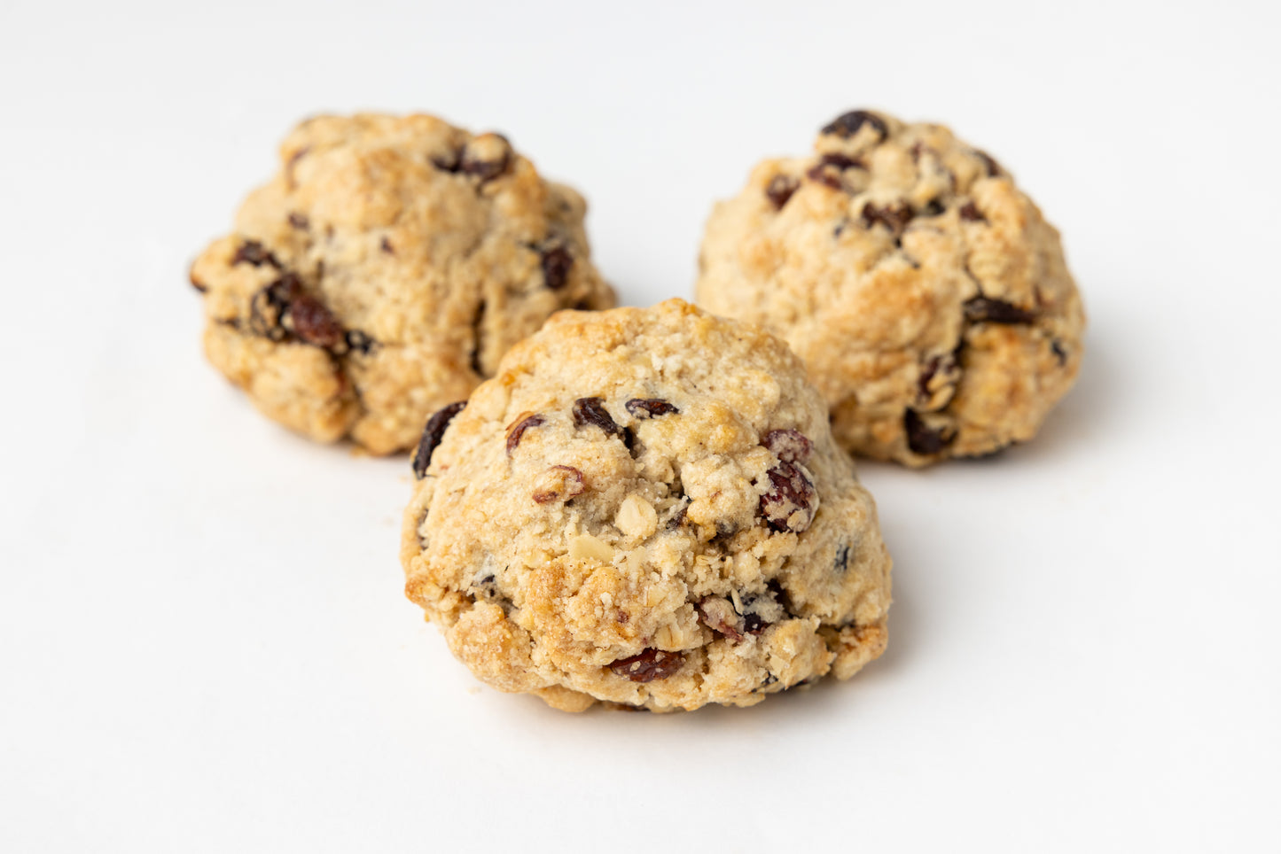 Three oatmeal raisin cookies on a white background
