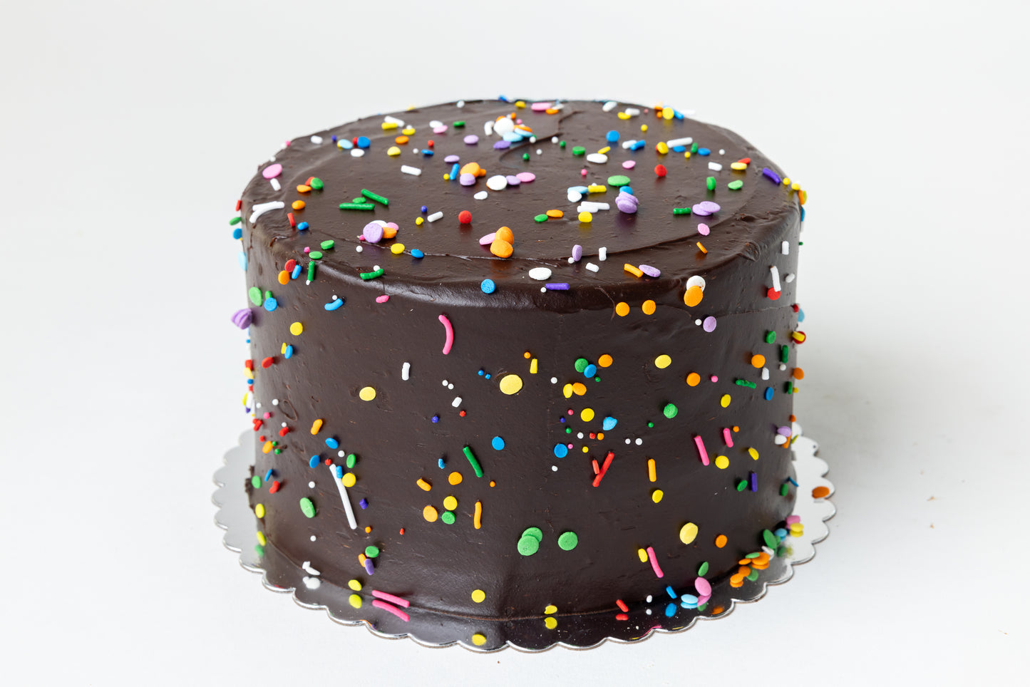 Chocolate cake with colorful sprinkles on a white background