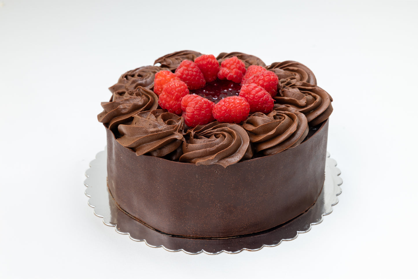 Chocolate cake with raspberry jam and real raspberries on a white background