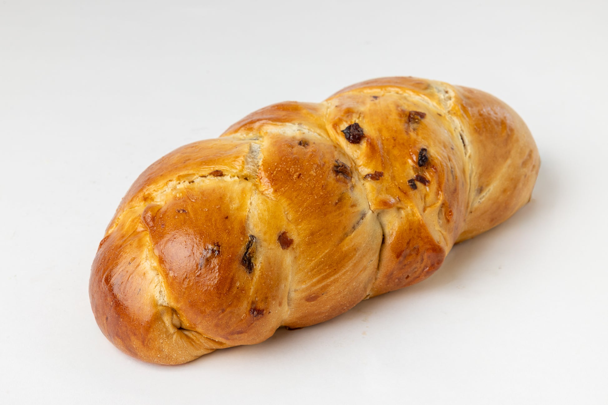 Braided bread loaf filled with raisins displayed on a white background