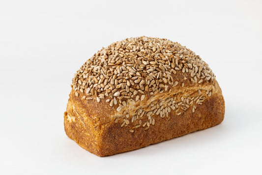 Loaf of bread covered with sunflower seeds on a white background