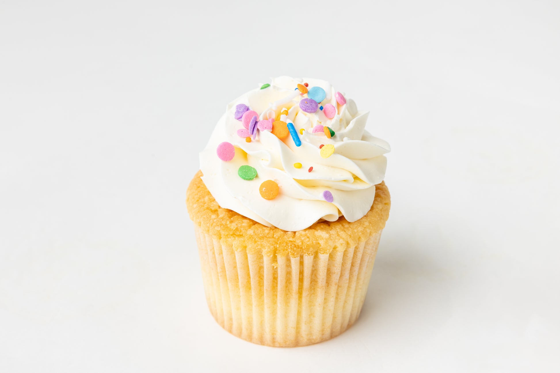 vanilla Cupcake with white frosting and colorful sprinkles on a white background
