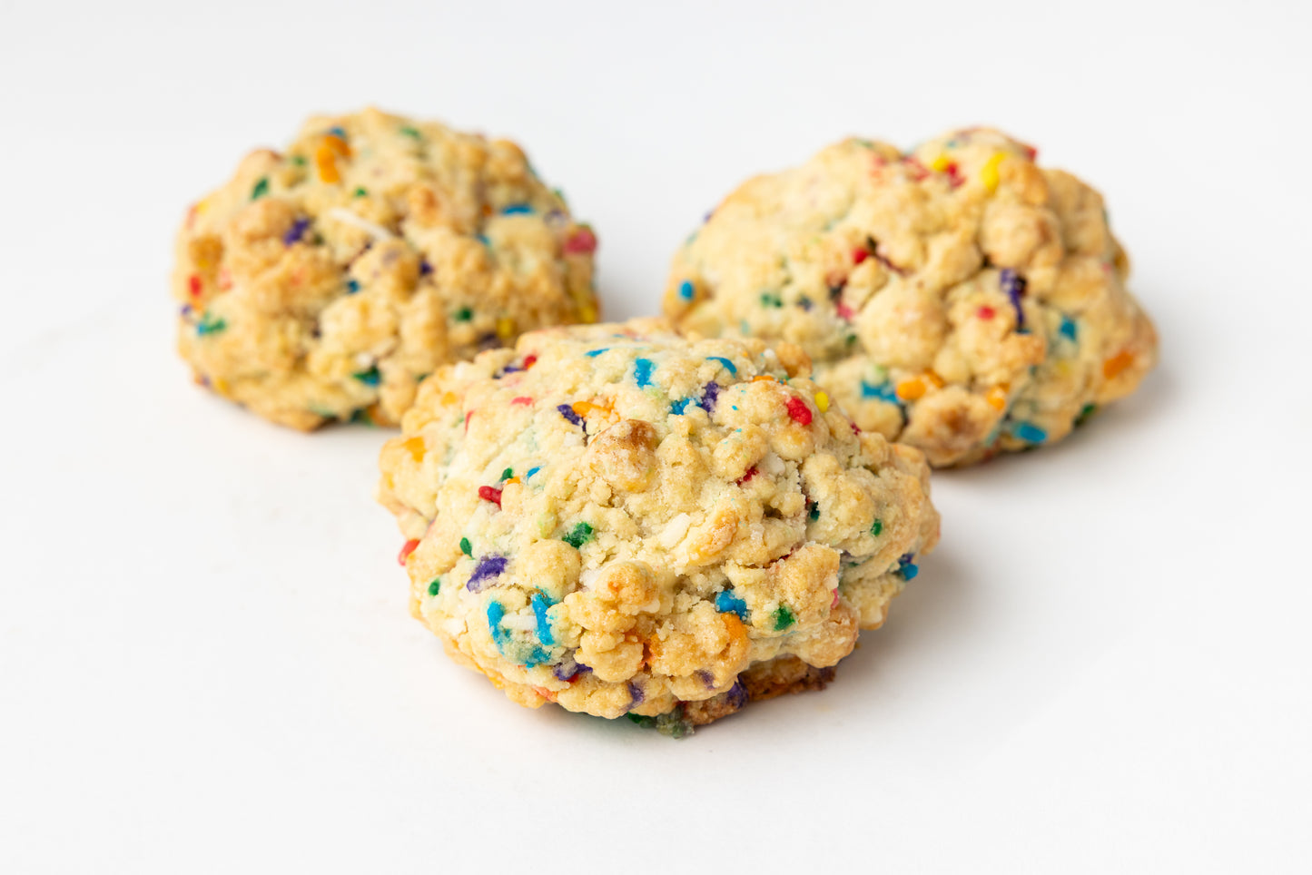 Three cookies with colorful sprinkles on a white background