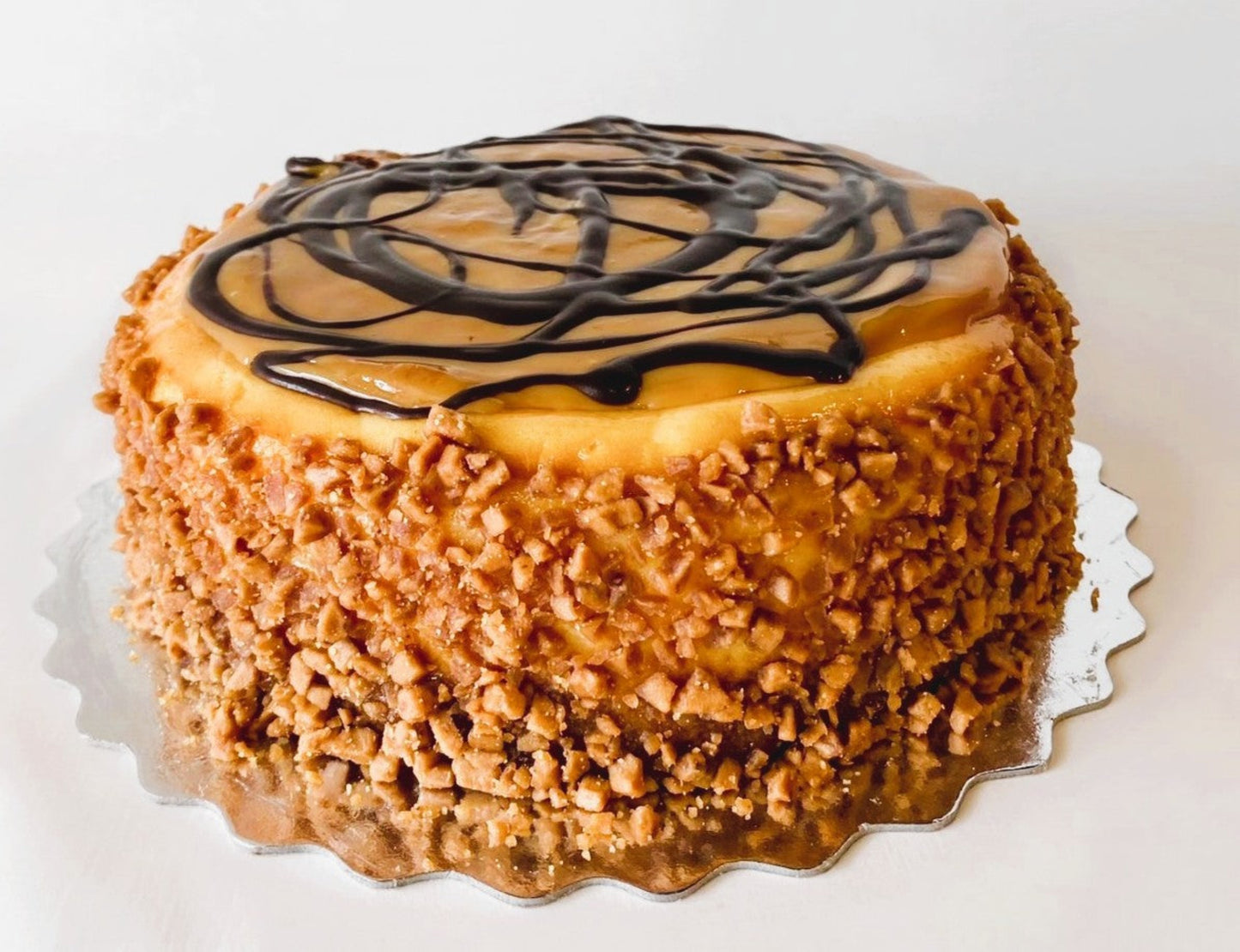 Cheesecake with dulce de leche, skor bits and chocolate drizzle on a white background